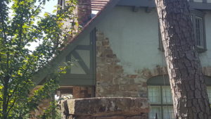 A picture of a house roof with brick detailing and green wooden trim